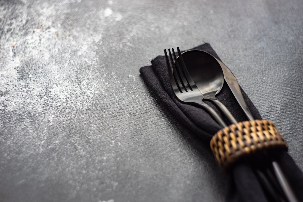 Dark silverware in matching napkin on counter with copy space