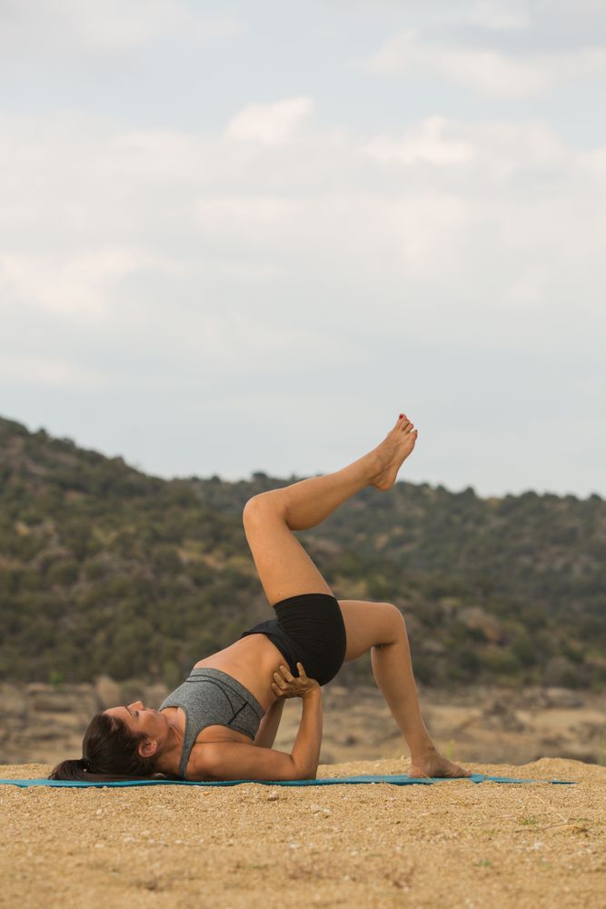 Woman practicing yoga outdoors near water