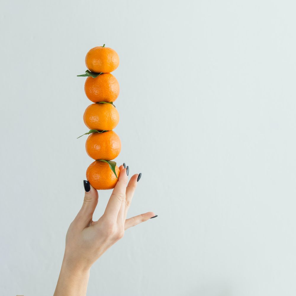 Hand holding stacked tangerines on bright background