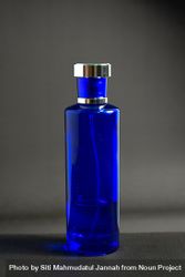 Blue perfume bottle in grey studio with copy space 4MGxYz