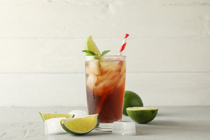 Glass with cold cola and citrus on grey cement background, space for text