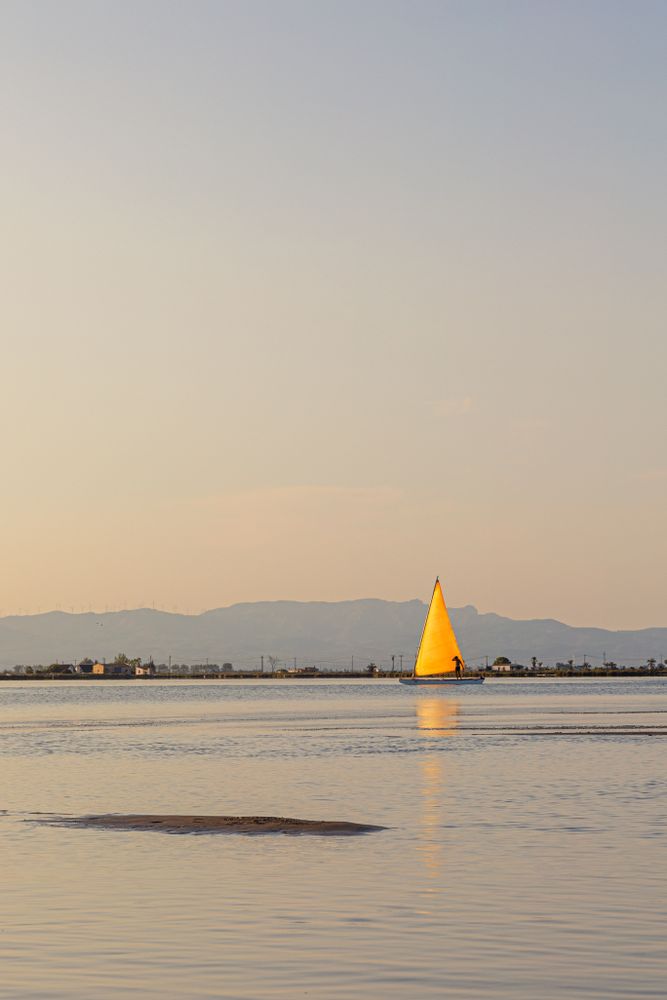 Yellow sailboat sailing in sea at dawn