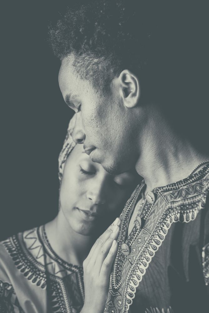 Woman with eyes closed clinging to ethnic man