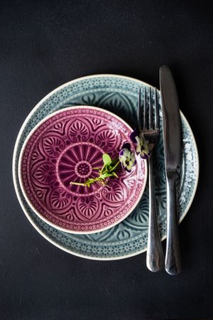Top view of spring table setting with delicate purple flowers on patterned plate