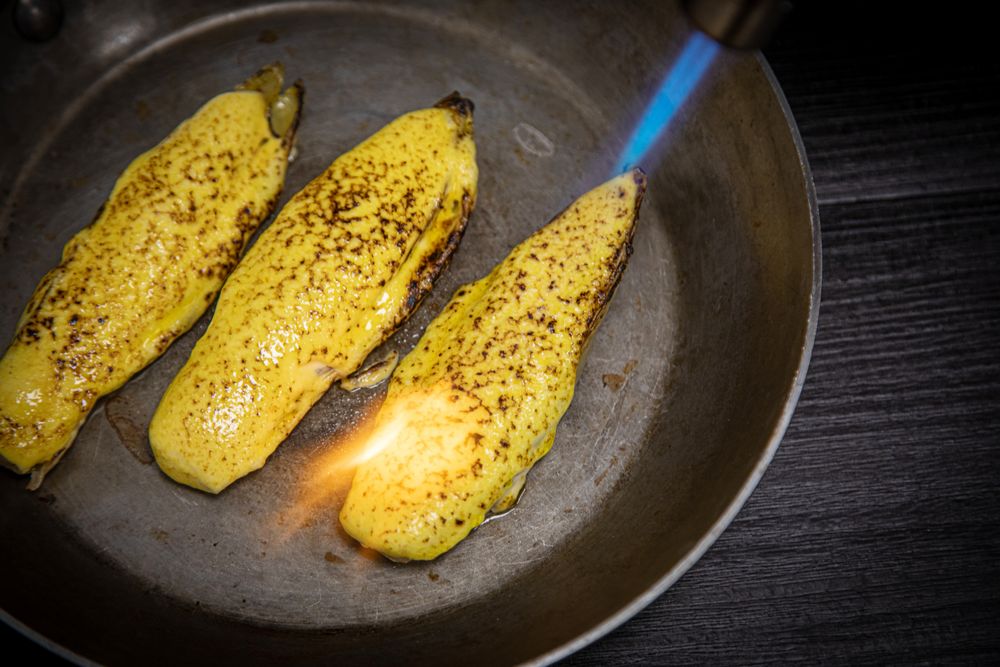 Person cooking endive with burner in pan