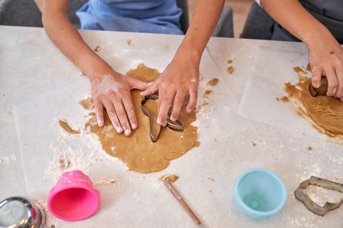 Crop unrecognizable kids cutting dough during cookies preparatio