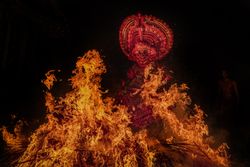Man performing Theyyam ritual form of dance worship surrounded by fire at night 4BEpe5