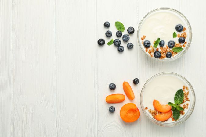 Flat lay composition with yogurt desserts and ingredients on wooden background