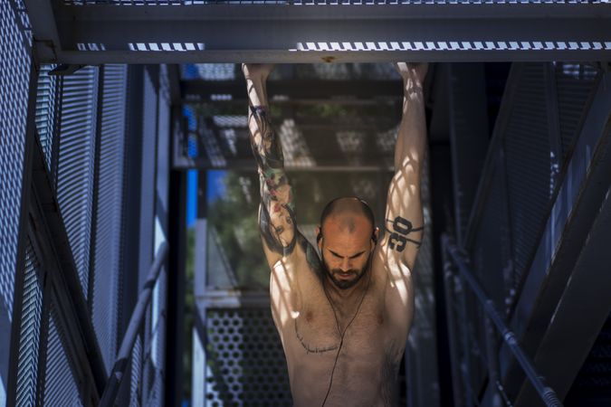 Muscular guy performing pull ups on street