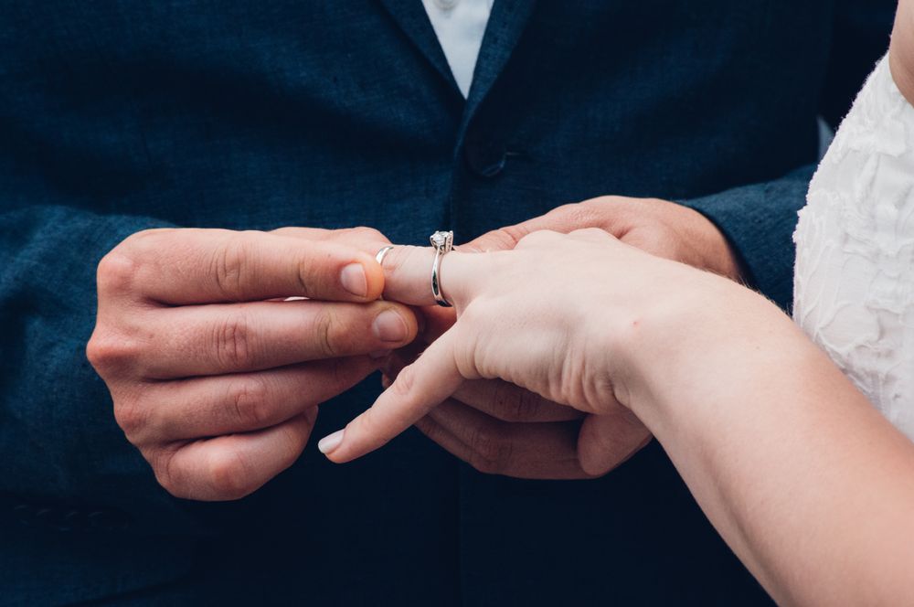 Groom putting a wedding ring on bride's finger