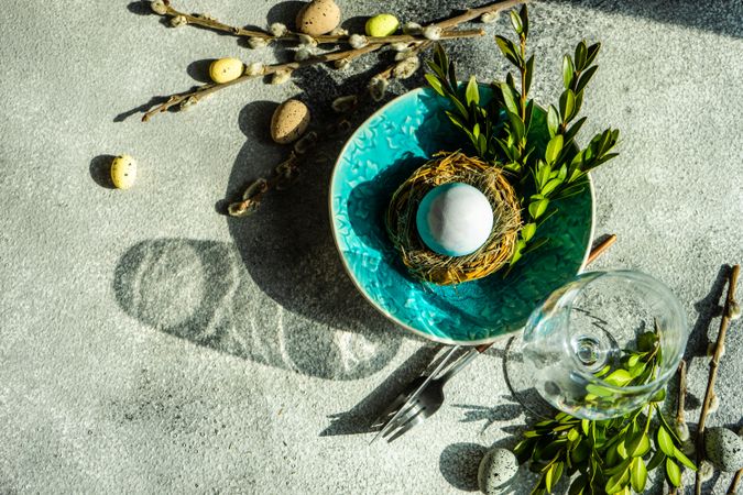 Top view of Easter table setting with teal bowl with decorative egg in nest