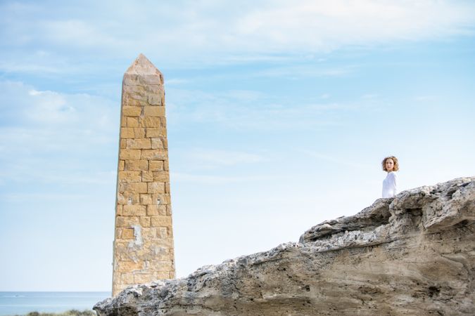 Young woman near brick monument and blue sky
