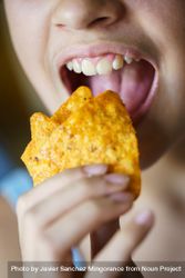 Mouth of girl biting into tortilla chips 5r9Em1