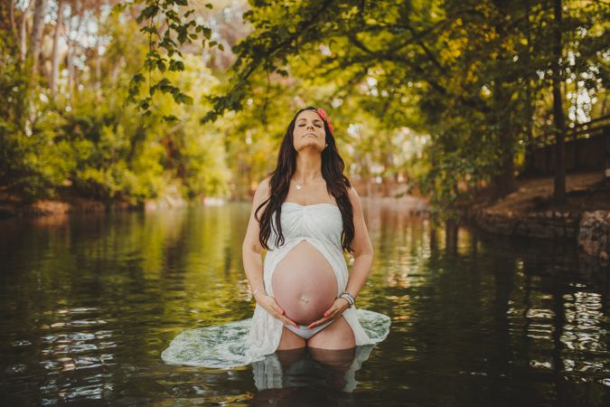 Pregnant woman standing in lake water