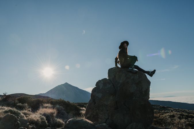 Woman sitting on rock in hillside