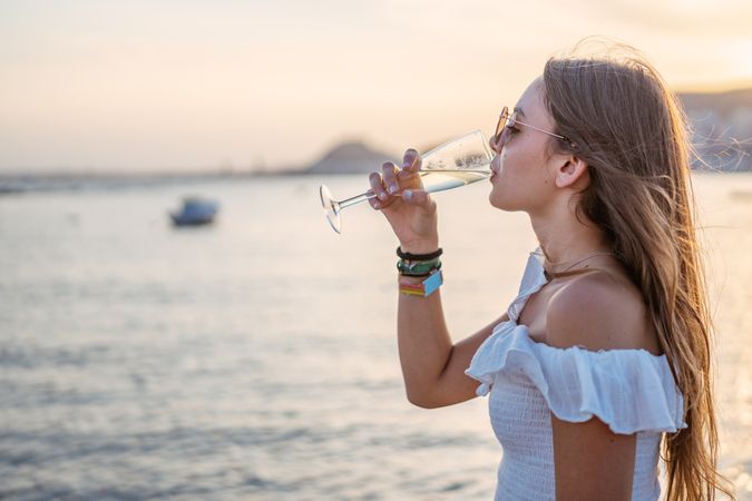 Young woman enjoying wine near sea