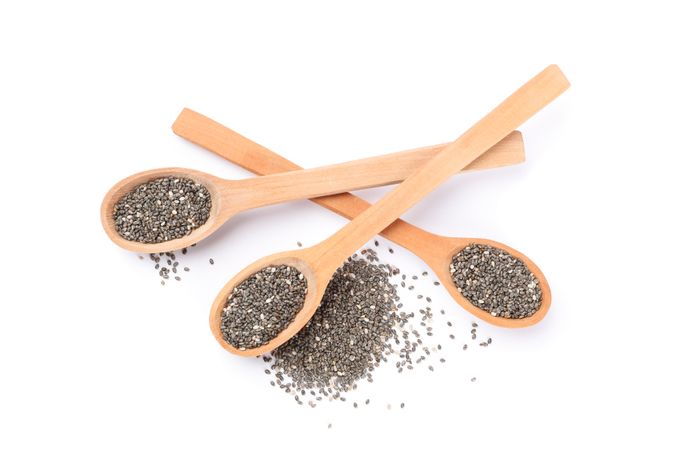 Chia seeds and wooden spoons isolated on blank background