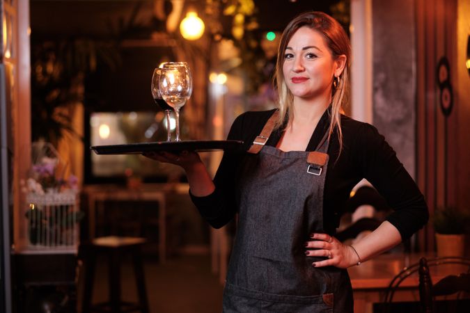 Cheerful waitress holding tray with wineglasses