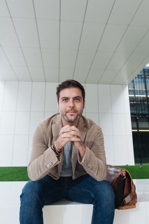 Cheerful manager sitting outside modern building
