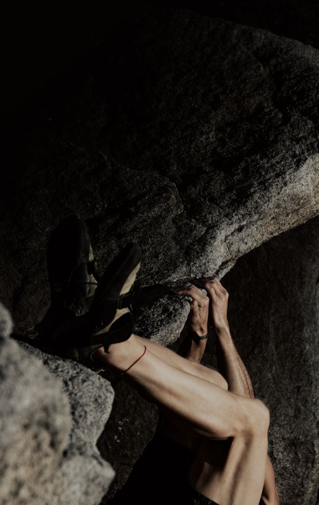 Man practicing rock climbing among large rocks in a forest