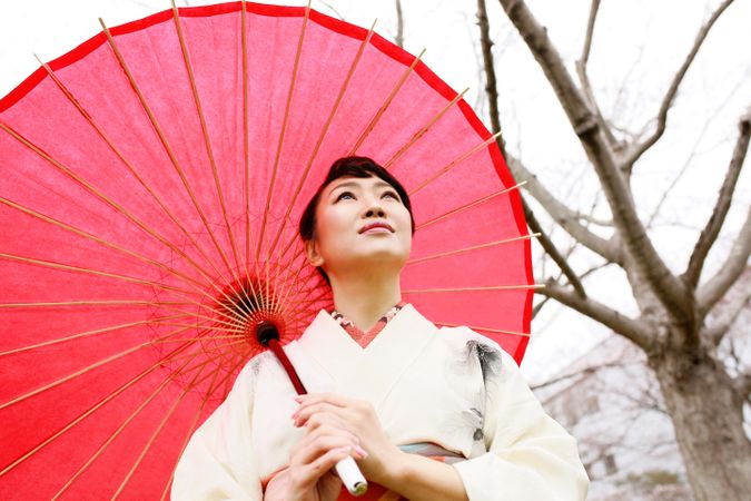 Woman in light floral kimono holding red umbrella