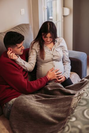 Happy husband touching belly of pregnant wife