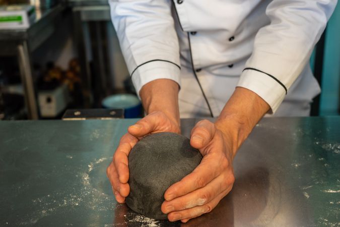 Person making ball of squid ink pasta dough