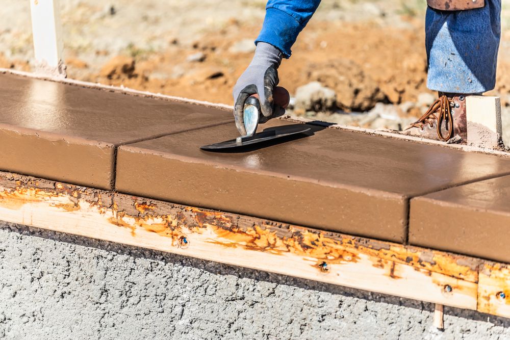 Construction Worker Using Trowel On Wet Cement Forming Coping Around New Pool