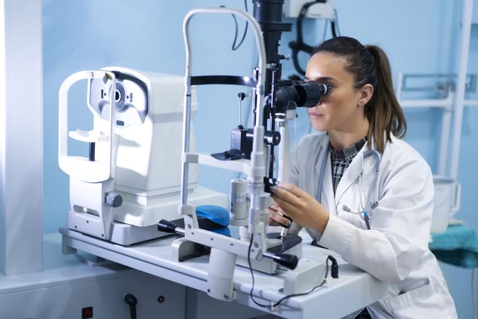 Medical woman looking through microscope