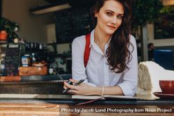 Beautiful woman sitting at coffee shop looking at camera 0LAxR5