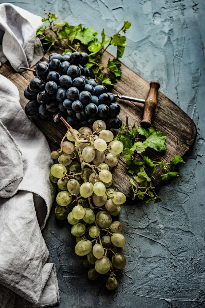 Top view of grapes on board with wine opener