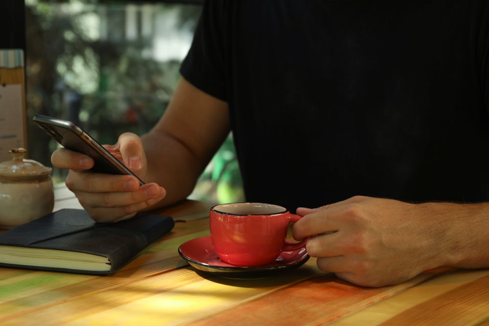 Man using phone and drink coffee in restaurant