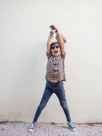 Excited kid raising hands up with ukulele