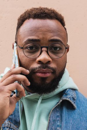 Black man talking on phone near wall