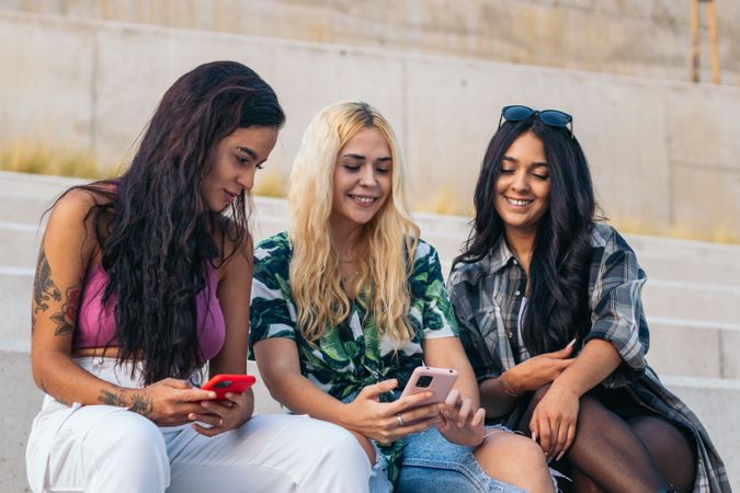 Diverse friends using smartphone outdoors