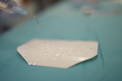 Drop of liquid on paper falling down from syringe