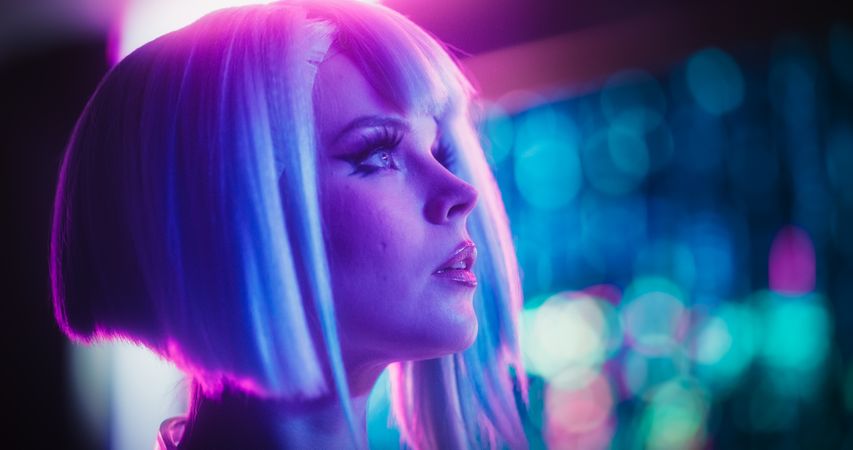 Close Up Portrait of a Stylish Young Cosplay Model with Blue Hair Looking at a Futuristic Cybernetic City with Neon Lights. Young Excited Female in a Cyberpunk Augmented Reality