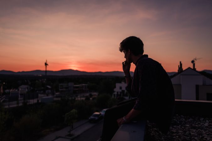 Young man smoking cigarette during sunset