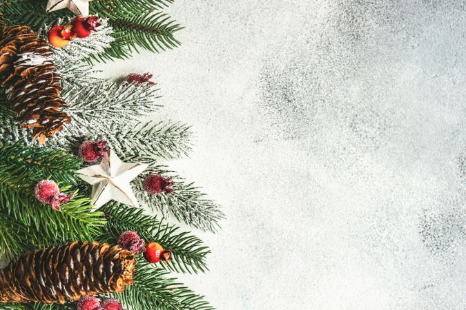 Christmas branch, pine cones, ornaments and holly on grey background with copy space