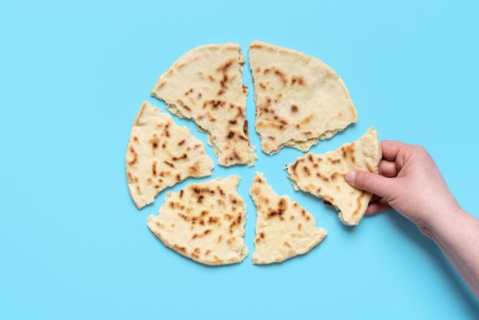 Indian flat bread above view. Woman taking a piece of naan bread