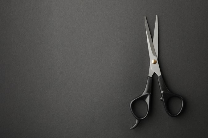 hairdresser scissors on dark background, space for text
