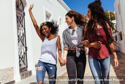 Young woman jumping in joy while walking with friends on a street 5kkgj5