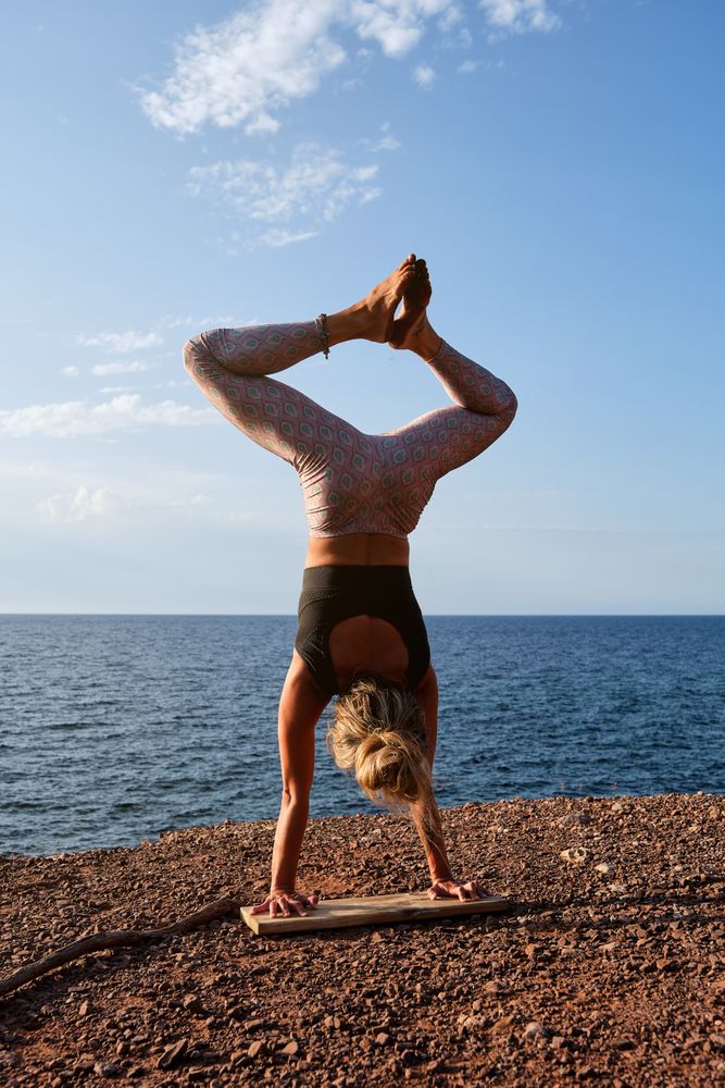 Barefoot sportswoman in Handstand pose on earthy seashore