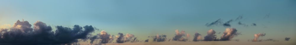 Thin banner of fluffy clouds in smokey blue sky