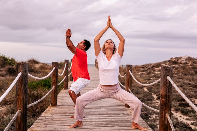 Adult couple meditating on wooden path