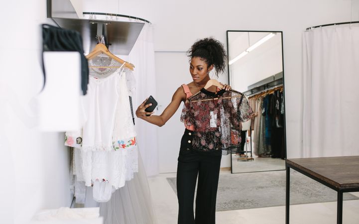 Fashion designer taking a selfie with a designer blouse in her fashion studio