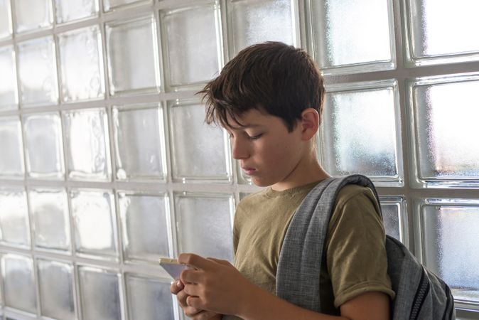 Dissapointed teenager texting while leaning on wall