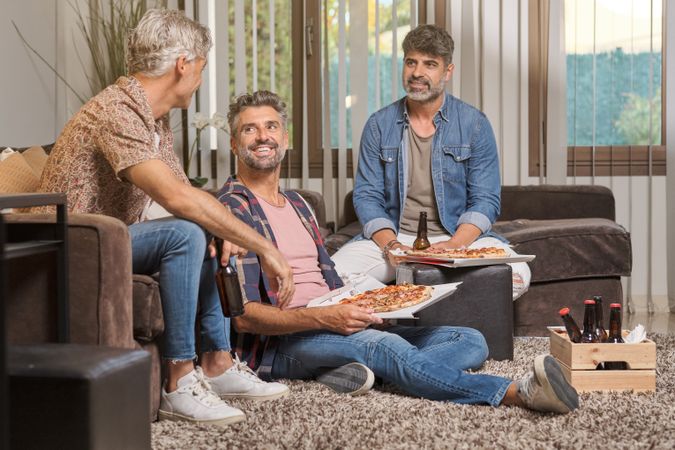Cheerful friends having fun with pizza and beer