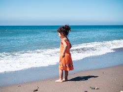 Little girl standing on beach and admiring view