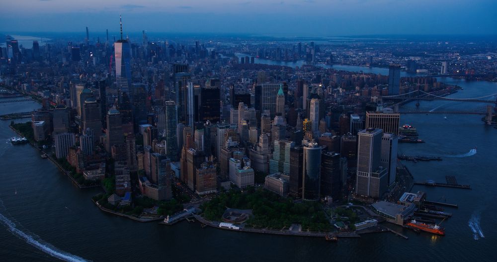 Evening Aerial View of Lower Manhattan Architecture. Panoramic Shot of Wall Street Financial District from a Helicopter. Office Buildings Next to Water Transportation in Hudson and East Rivers